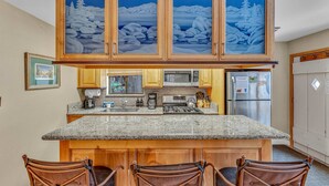 A kitchen with a central island, wooden cabinets, a microwave, a refrigerator, and a coffee maker.