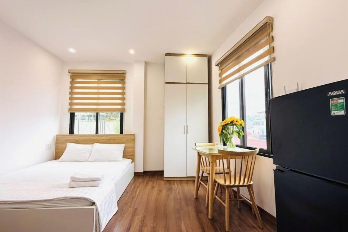 Ein Hotelzimmer mit einem Bett, einem Holztisch mit Stühlen, einem Kühlschrank und einem Kleiderschrank.