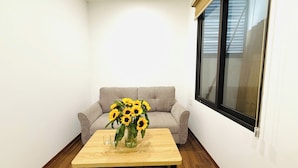 Un salon avec un canapé gris, une table basse en bois et un vase rempli de tournesols.