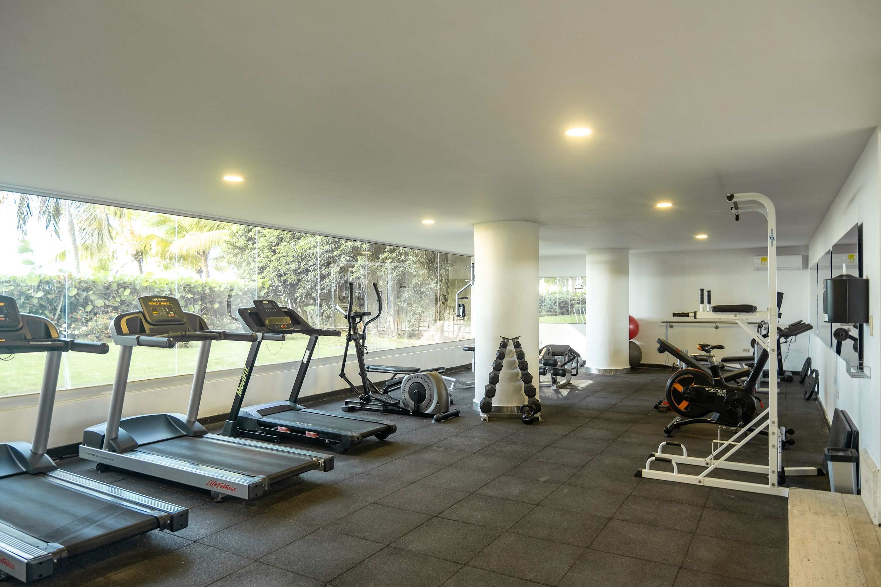 Ein Fitnessstudio mit Laufbändern, Crosstrainern und Gewichten.