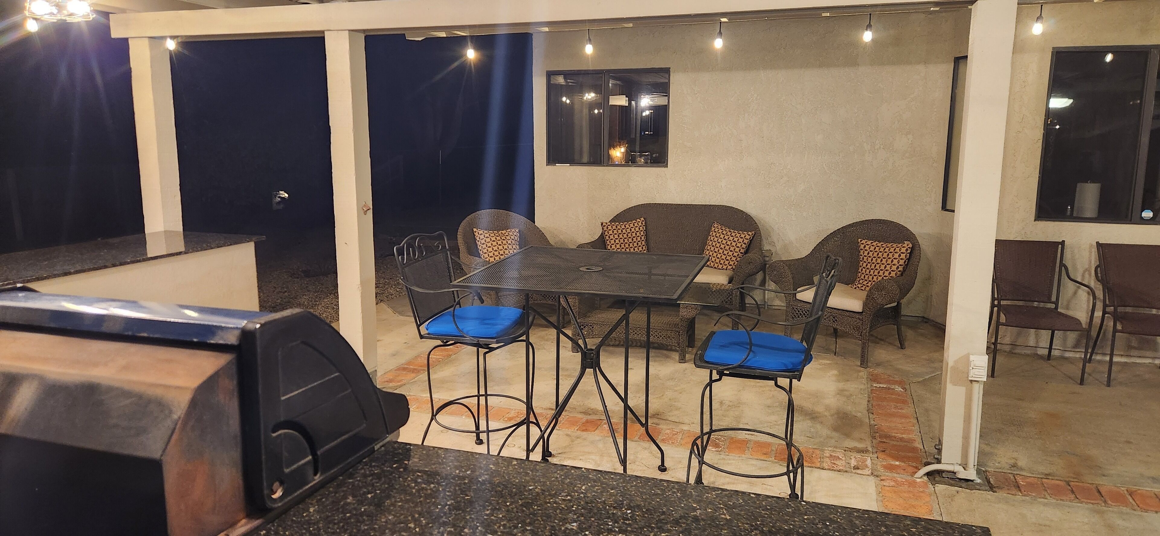 An outdoor patio area with a dining table, chairs, and a grill.