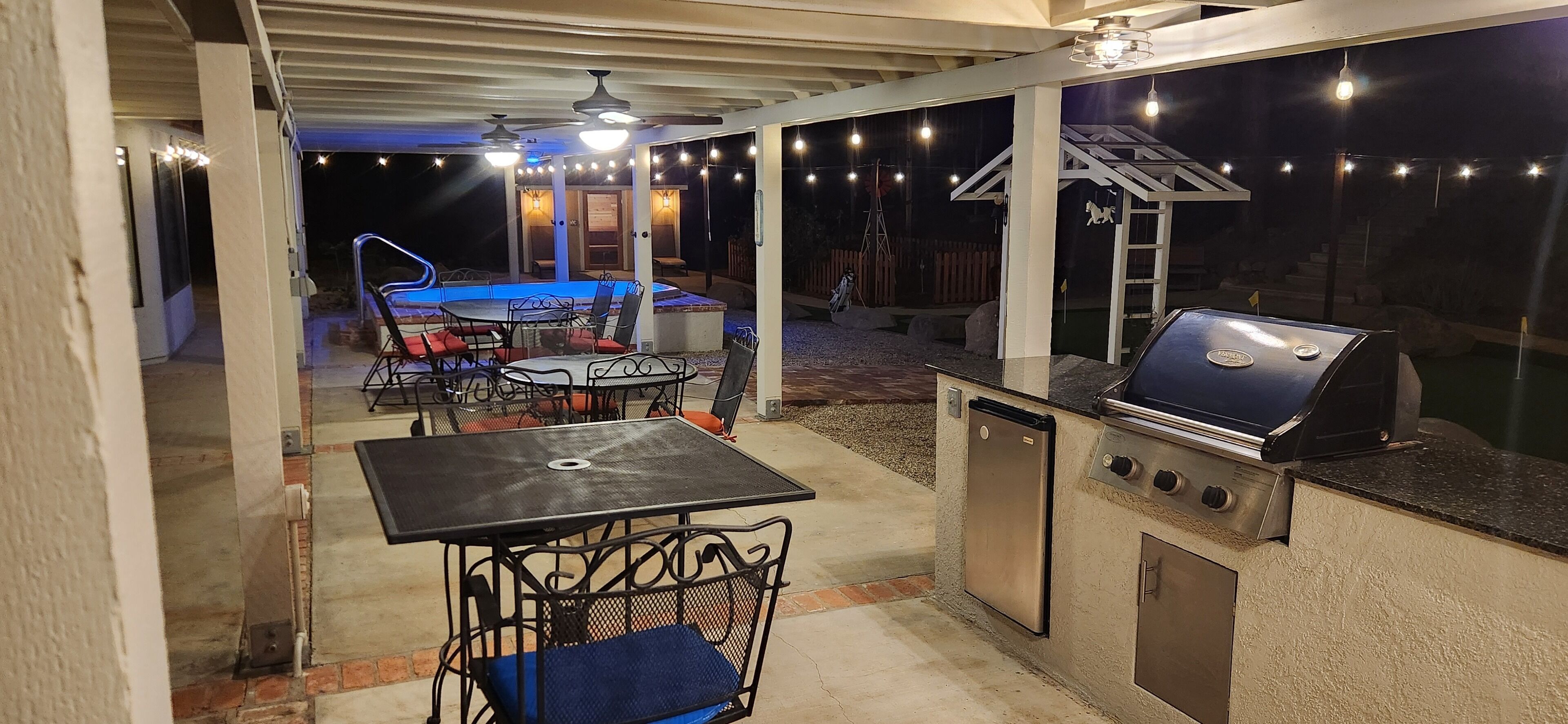 An outdoor patio with a grill, a pool table, and seating.