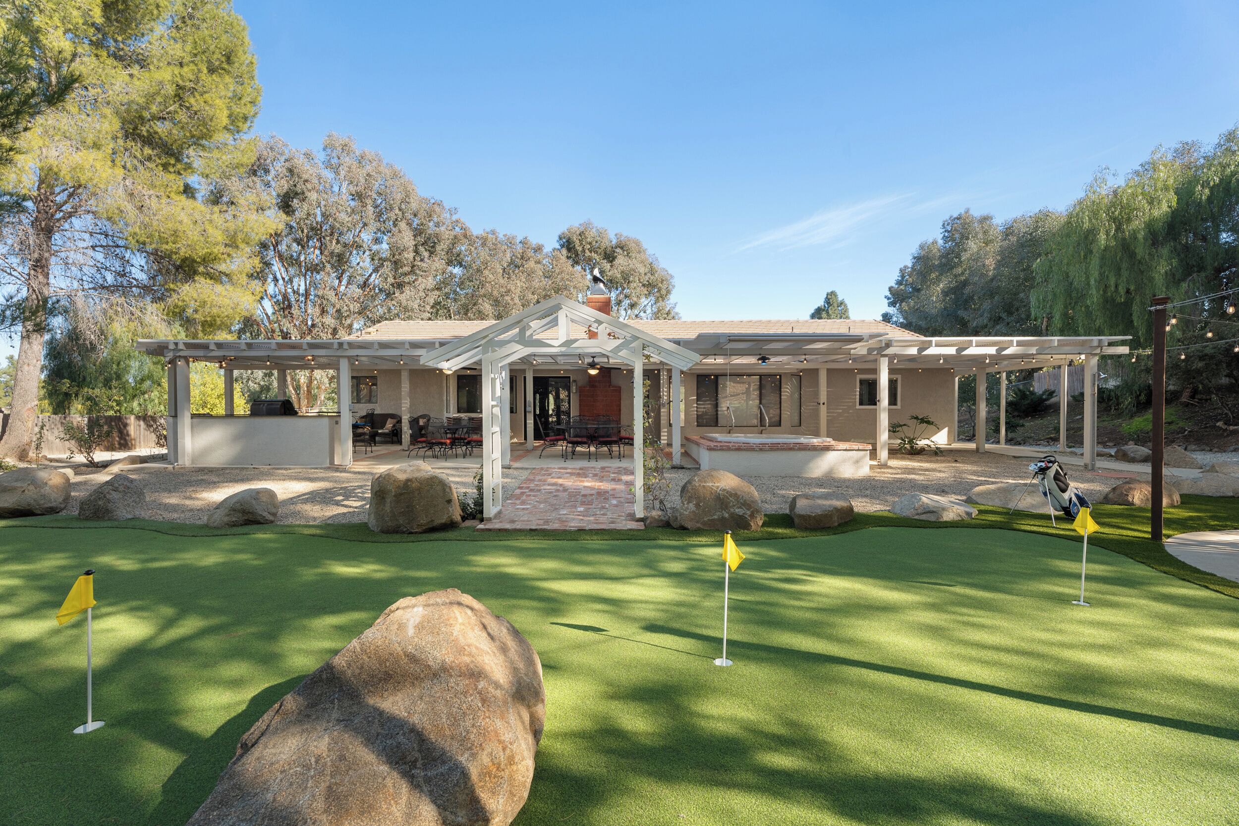A golf course with a clubhouse, large rocks, and a well-maintained lawn.
