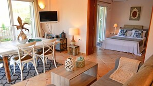 Une pièce confortable avec un lit, un canapé, une table à manger avec des chaises, un téléviseur et une petite table avec une lampe.