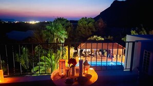 Une terrasse sur le toit avec une piscine, des palmiers et une vue imprenable sur le coucher de soleil.