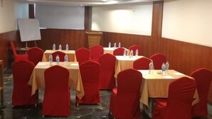 A conference room with multiple tables and chairs, equipped with water bottles, in a room with a marble floor and wooden paneling on the walls. - King S Crown (Barasat)