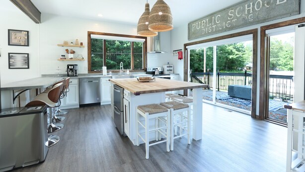 A modern kitchen with a large island, bar stools, and a view of the outdoors.
