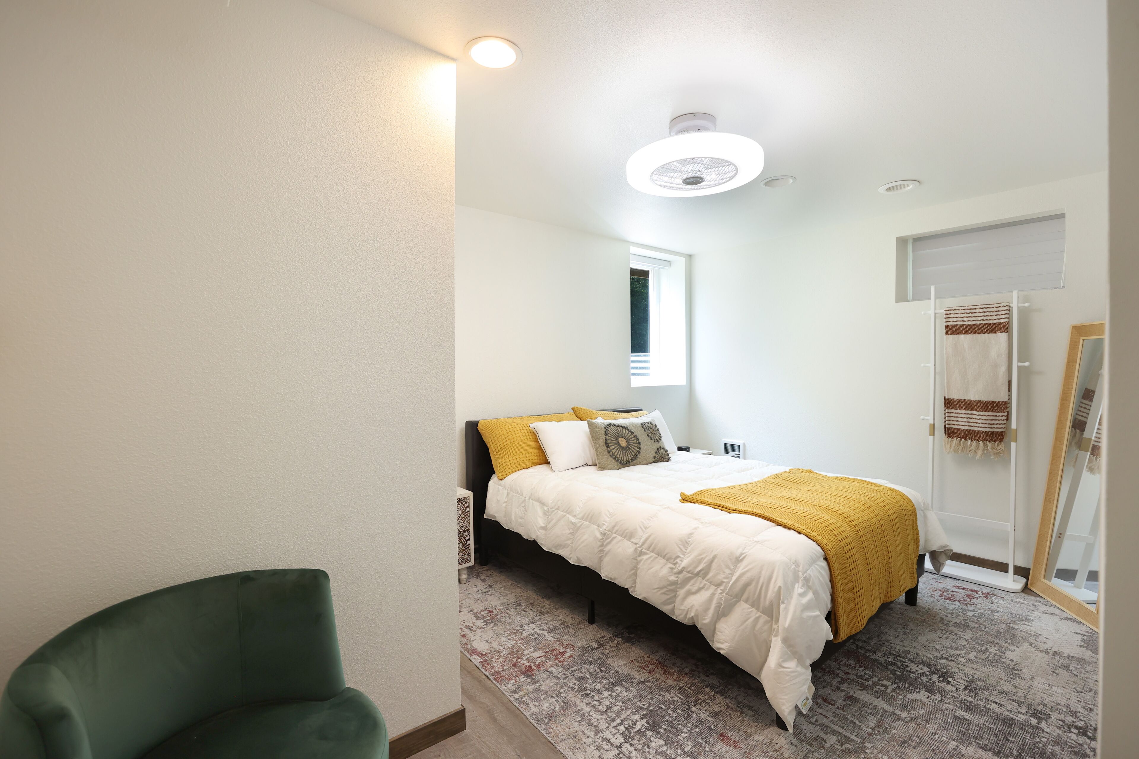 A bedroom with a bed, a chair, a window, and a door.