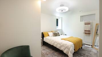 A bedroom with a bed, a chair, a window, and a door.