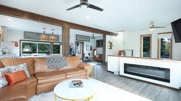 A spacious living area with a leather sofa, a white coffee table, and a fireplace.