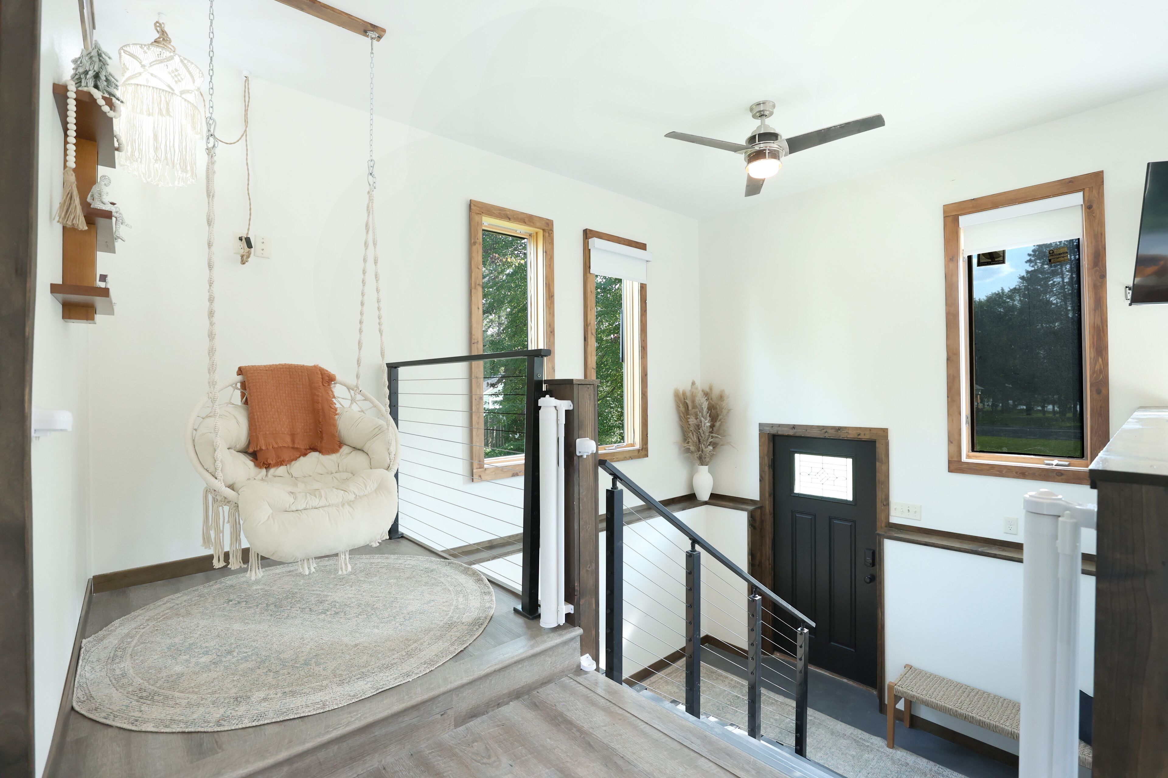 A staircase with a wooden handrail and a white wall with a window.