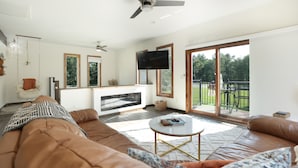 A spacious living room with a large brown leather sofa, a round coffee table, and a fireplace.