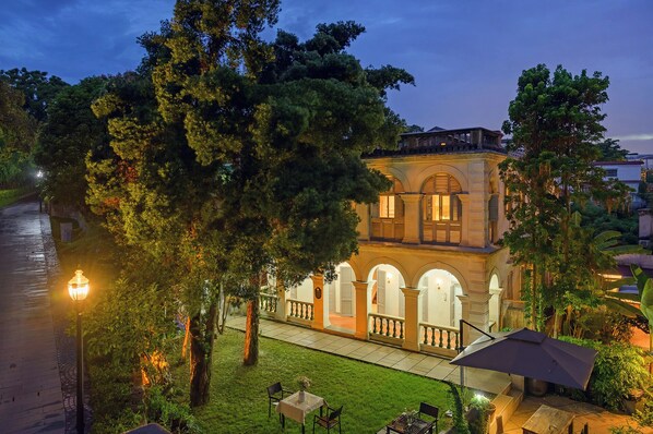 Un edificio con un cortile interno, circondato da alberi e un vialetto.