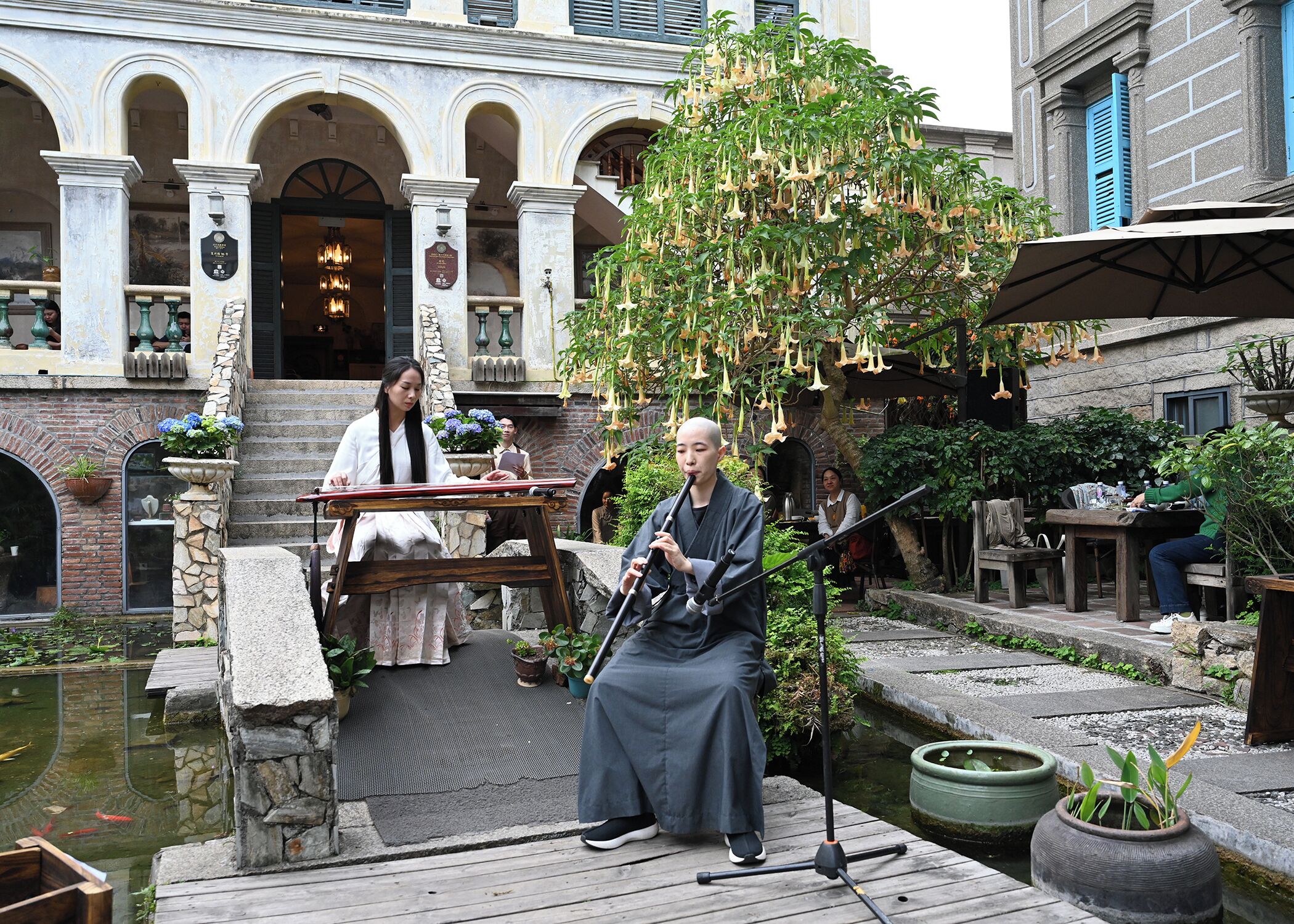 An outdoor courtyard with a fountain, a wooden deck, and a building with arches and columns.