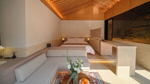 Een moderne, goed verlichte kamer met een houten plafond, een groot bed, een zithoek en een decoratieve vaas met bloemen.