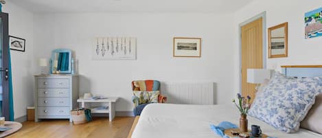A bedroom with a bed, dresser, chair, and artwork on the walls.