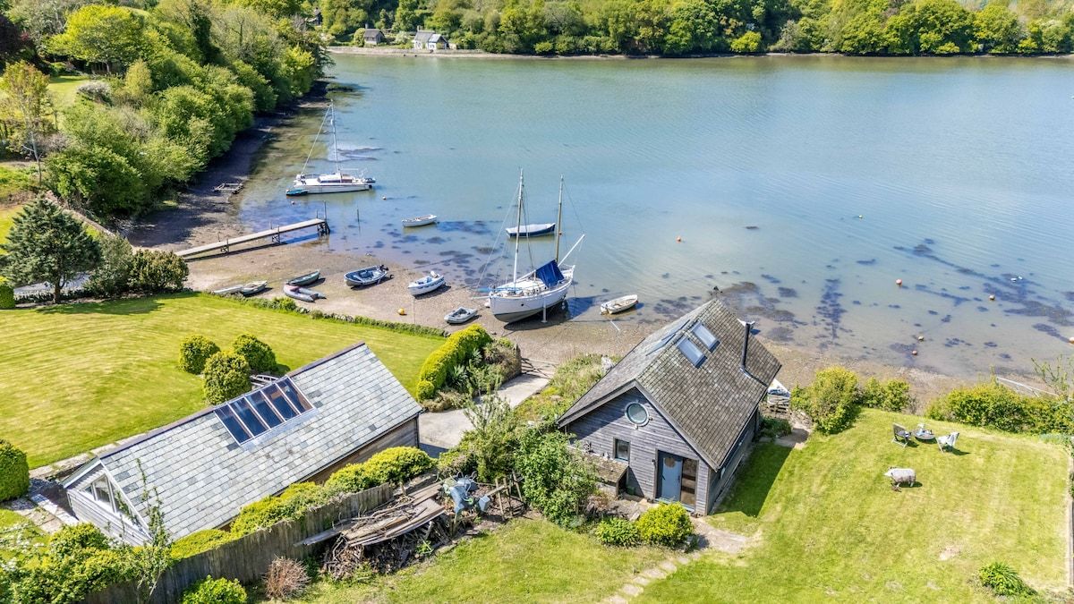 A lakeside property with a dock, boats, and a house with a sloped roof.