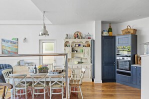 A kitchen with a dining area, wooden cabinets, and a hanging light fixture.
