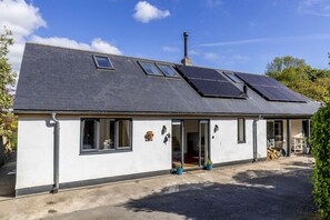 En toetages bygning med skråtag, solpaneler og garage.