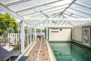 Et drivhus med swimmingpool, glasdøre og flisegulv.