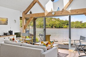 En moderne stue med et stort vindue, en sofa, et fjernsyn og et træloft.