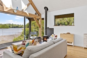 A modern living room with a sofa, a fireplace, and a view of a lake.