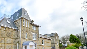 A large stone building with multiple stories, a prominent gabled roof, and a small balcony on the upper floor. - Shanklin Stunning Sea Views (Shanklin)