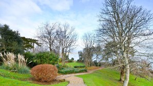 A pathway leading through a garden with various plants and trees. - Shanklin Stunning Sea Views (Shanklin)