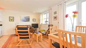 A living room with a sofa, chairs, a TV, and a window with curtains. - Shanklin Stunning Sea Views (Shanklin)