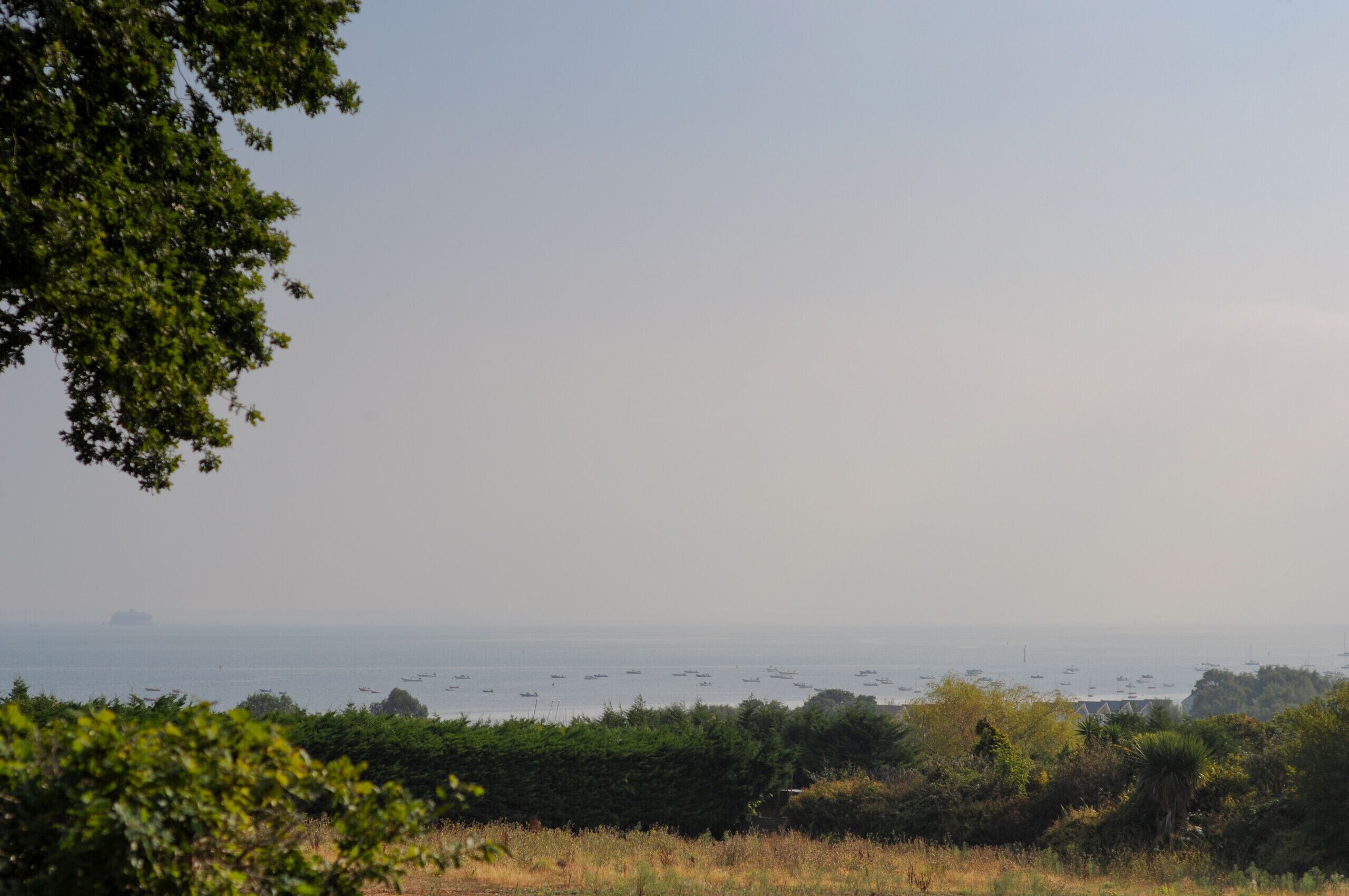 A coastal landscape with a view of the sea and boats.
