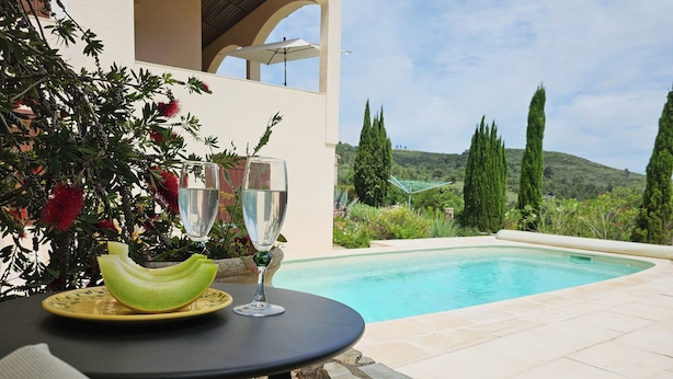 A poolside setting with a table, a glass of water, and a plate with a fruit slice. - Charming villa with a pool and beautiful views (Montouliers)