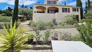 A two-story house with a garden, a pergola, and a tiled roof. - Charming villa with a pool and beautiful views (Montouliers)