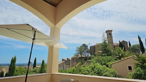 A balcony with a view of a historic building and surrounding greenery. - Charming villa with a pool and beautiful views (Montouliers)