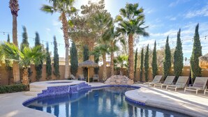A swimming pool with a blue mosaic border, surrounded by palm trees and lounge chairs. - 12 Mi to the Strip: Las Vegas Home w/ Luxe Oasis! (Las Vegas)