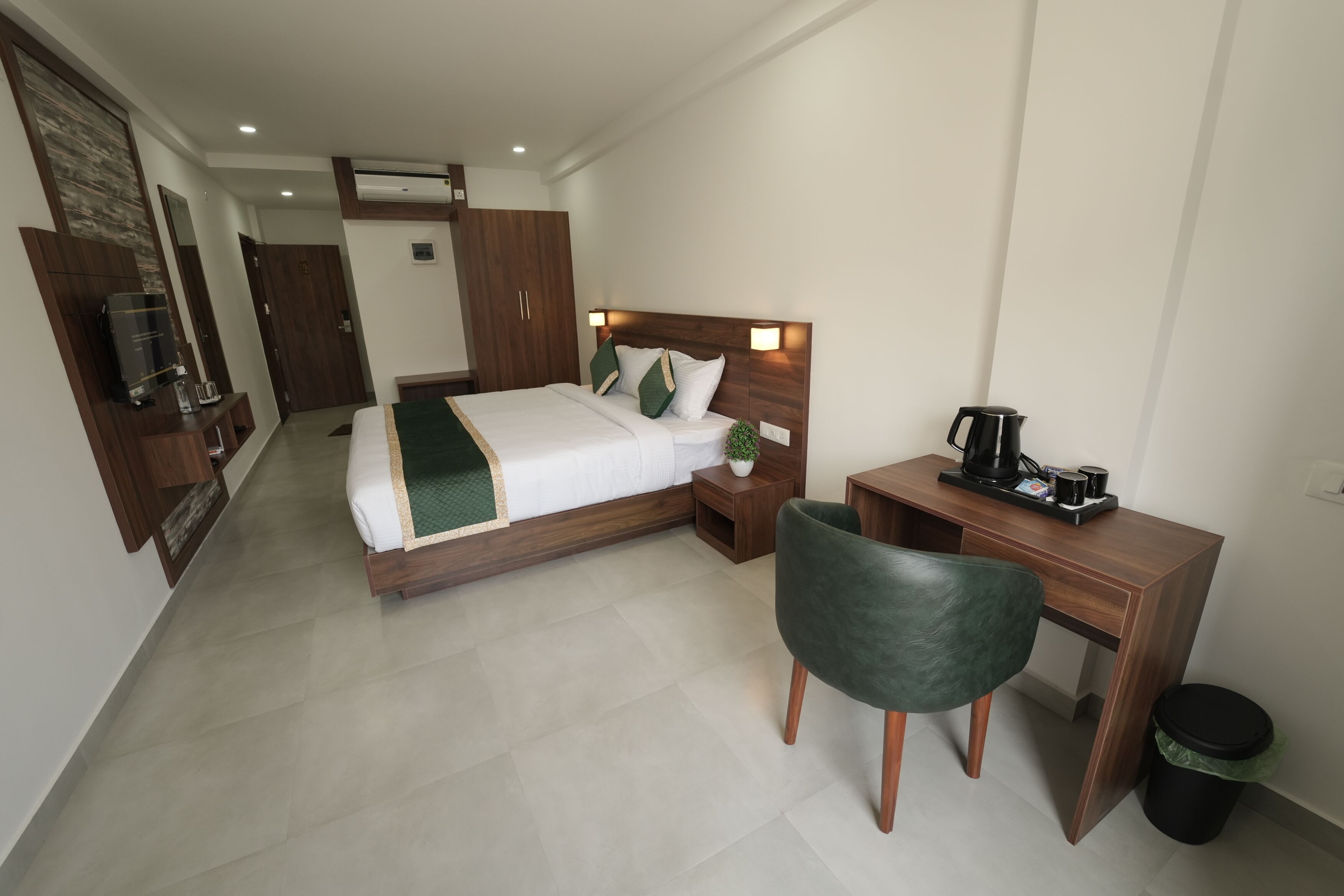 A hotel room with a bed, desk, chair, and a small trash bin.