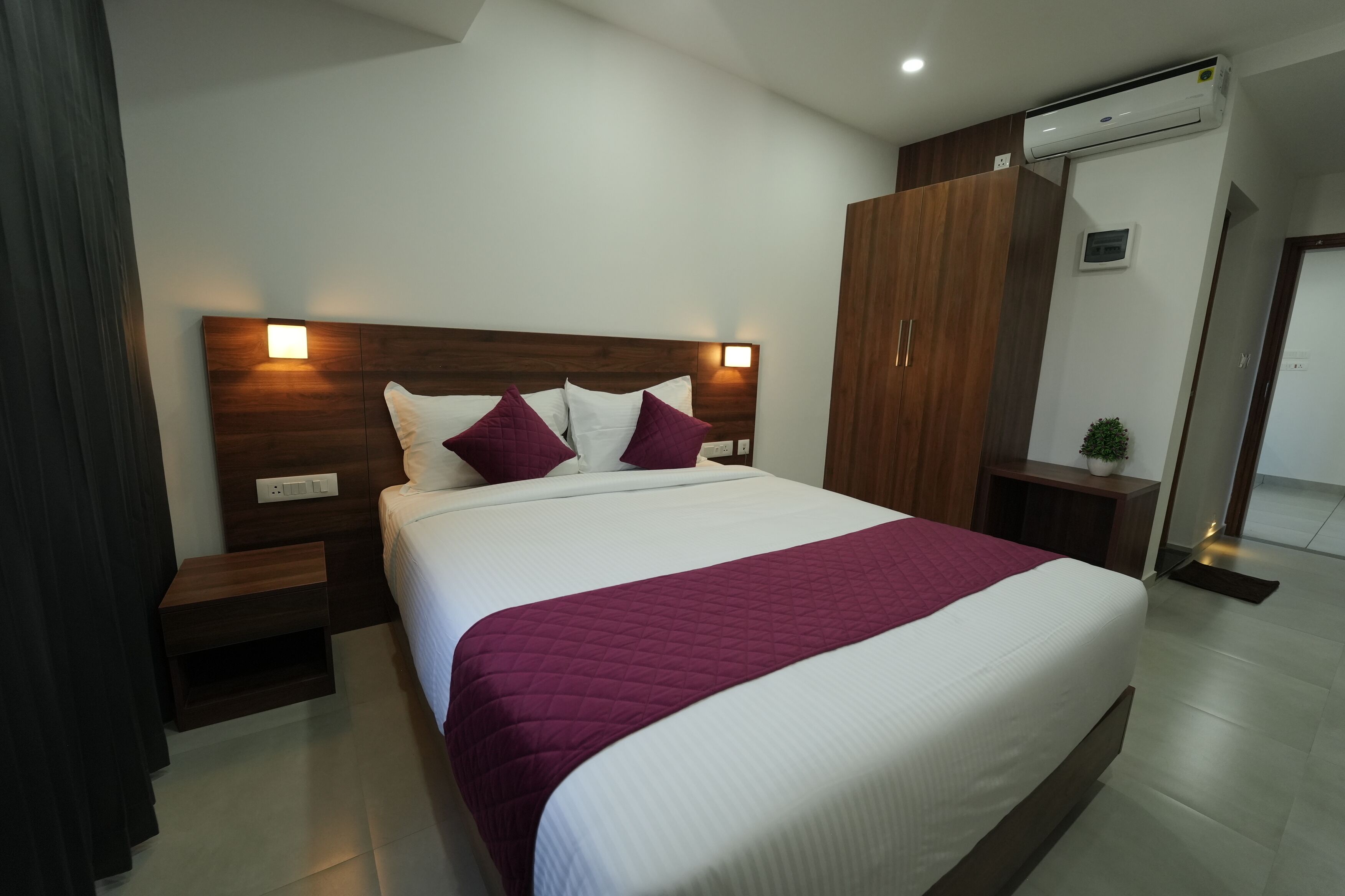 A modern hotel room with a large bed, wooden headboard, and bedside tables.