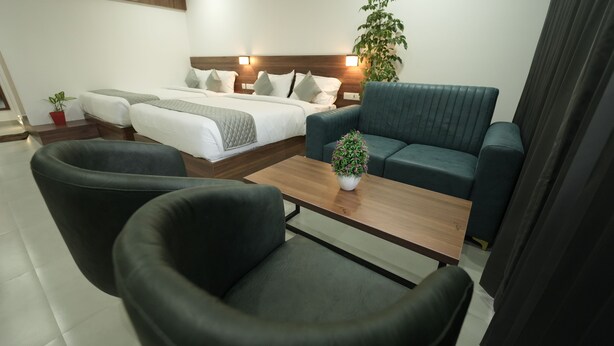 Een moderne hotelkamer met een bed, twee banken, een bijzettafeltje en een potplant.