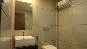 Een moderne badkamer met een wit wastafelmeubel, toilet en douchehoek.
