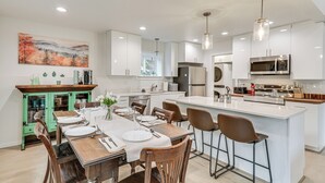 A modern kitchen with white cabinetry, a central island, and bar stools. - Near Rivers & Boating: Home w/ Hot Tub in Longview (Longview)