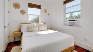 A bedroom with a large bed, two bedside tables, a window with blinds, and a radiator. - Stylish Apt Near Lake Travis w/ Entertainment (Austin)