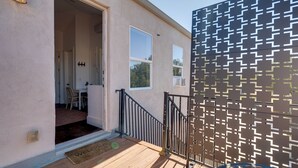 A wooden deck leading to a house with a patterned fence, a welcome mat, and a visible door. - Stylish Apt Near Lake Travis w/ Entertainment (Austin)