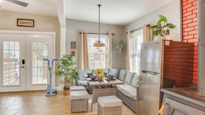 A modern kitchen with a built-in stove, a dining area with a sofa and table, and a large window with curtains. - 10 Mi to Dtwn Kansas City: Cozy Studio w/ Grill! (Kansas City)