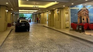 A hotel corridor with a car parked in the center, a chandelier, and a large mural of a monument on the wall. - Champs Elysees Homestay by Landmark (Kampar)