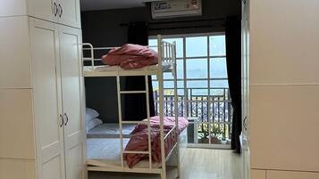 Een kamer met stapelbedden, een garderobe en een raam met uitzicht.