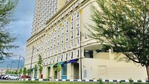 A high-rise hotel with multiple floors, a curved facade, and a parking area in front. - Champs Elysees Homestay by Landmark (Kampar)