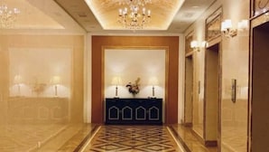A hallway with a geometric patterned floor, a reception desk with two lamps, and a chandelier. - Champs Elysees Homestay by Landmark (Kampar)