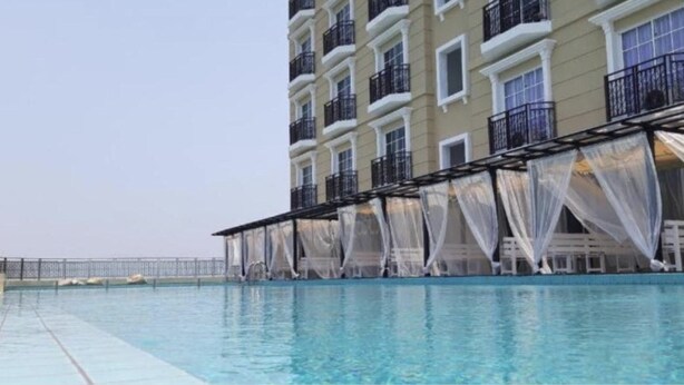 A swimming pool with a covered area and a building with multiple balconies in the background. - Champs Elysees Homestay by Landmark (Kampar)
