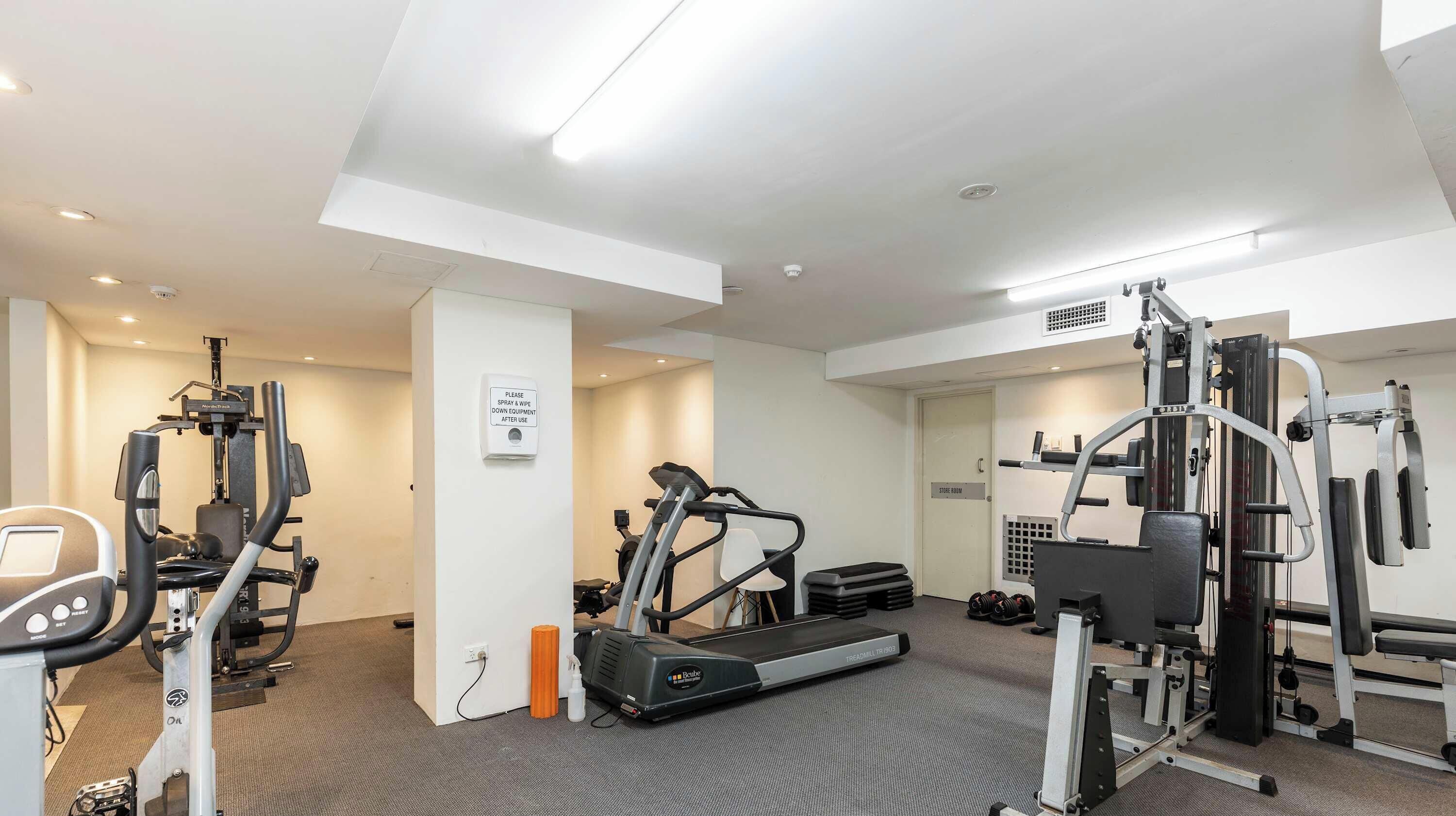 A gym with cardio machines, weightlifting equipment, and a treadmill.