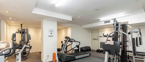 A gym with cardio machines, weightlifting equipment, and a treadmill.