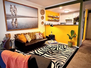 Un salon avec un canapé, un tapis à motifs zébrés, une table basse et un tableau accroché au mur.